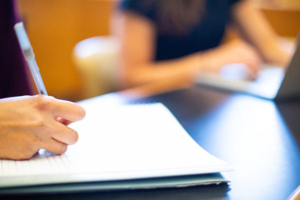 Image of student&#039;s hand taking notes in a notebook